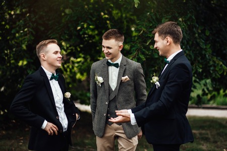 happy and young groom and his friends standing together outdoorsの写真素材