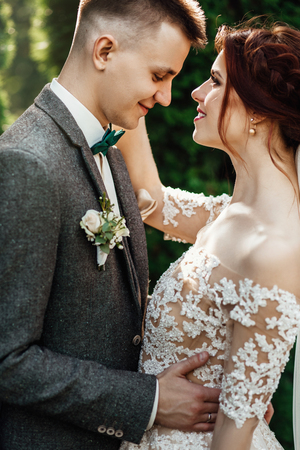 beautiful and young couple standing together near the green bushの写真素材