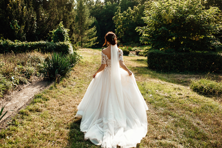 bride in a dress standing and walking in a green gardenの写真素材