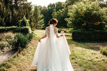 The beautiful bride in a white poses in the parkの写真素材