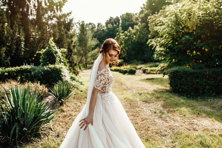 bride in a dress standing and walking in a green gardenの写真素材