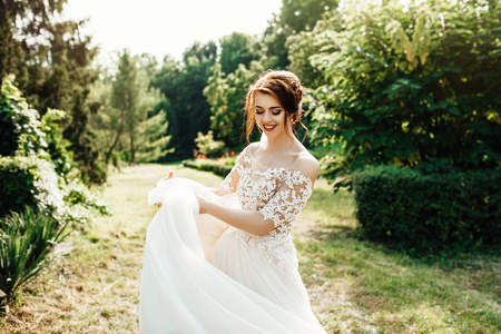 bride in a dress standing and walking in a green gardenの写真素材