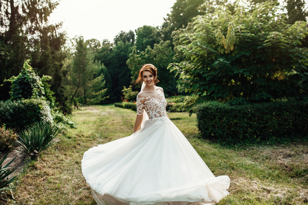 bride in a dress standing and walking in a green gardenの写真素材