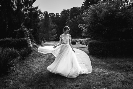 bride in a dress standing and walking in a green gardenの写真素材