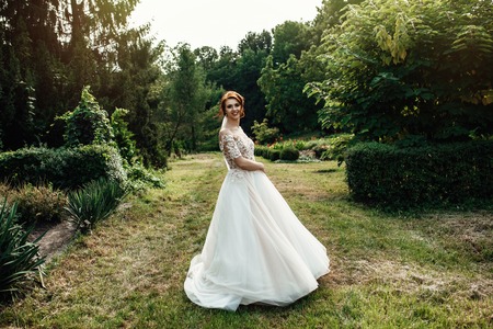 bride in a dress standing and walking in a green gardenの写真素材