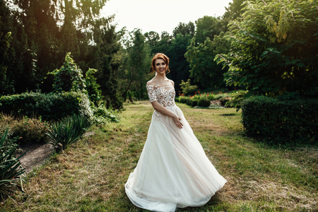 bride in a dress standing and walking in a green gardenの写真素材