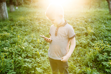 Little boy with the phone in his hands outdoors.の写真素材