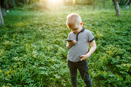 Little boy with the phone in his hands outdoors.の写真素材