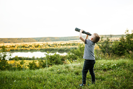 little boy looking into telescope eyepieceの写真素材