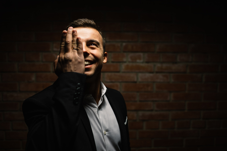 fashionable man on a black background holds his hand in the faceの写真素材