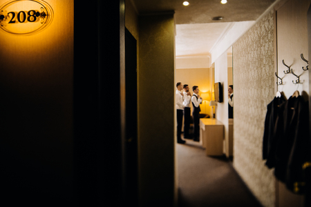 stylish groomsmen helping happy groom getting ready in the morniの写真素材