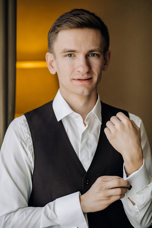 stylish groom portrait at the window while getting ready in theの写真素材