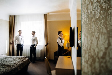 stylish groom laughing and having fun with groomsmen while gettiの写真素材