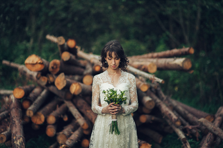 beautiful caucasian bride in wedding dress with bouquet posing iの写真素材