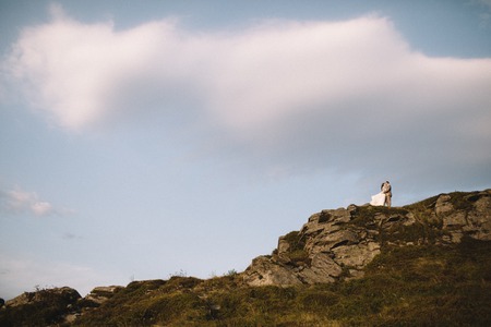 Romantic couple standing together holding hands in the mountainsの写真素材