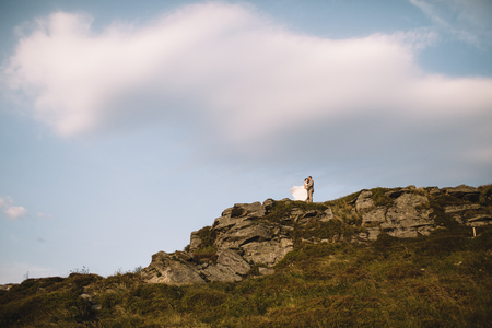 Romantic couple standing together holding hands in the mountainsの写真素材