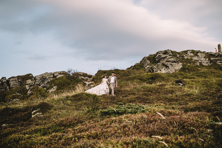 Romantic couple standing together holding hands in the mountainsの写真素材