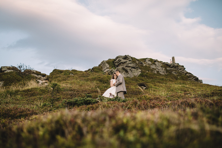 Romantic couple standing together holding hands in the mountainsの写真素材