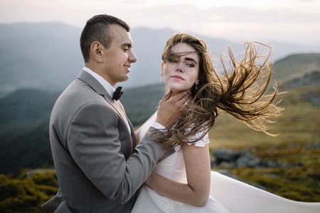 Romantic couple standing together holding hands in the mountainsの写真素材