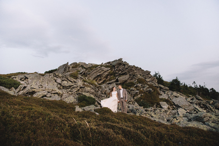 Romantic couple standing together holding hands in the mountainsの写真素材