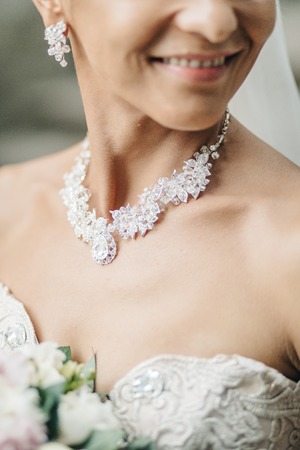 Stunning bride with red bouquet stands on the streetの写真素材
