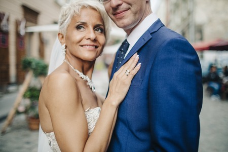 Happy smiling newlyweds walking outdoors, kissing and embracingの写真素材