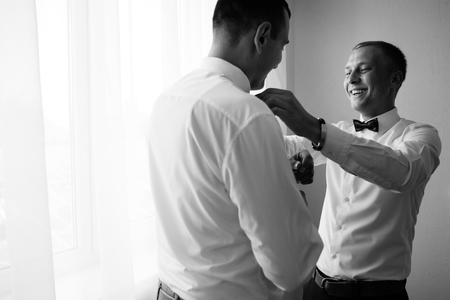 Handsome groom preparing for wedding ceremony in hotel roomの写真素材