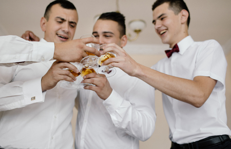 A group of handsome groomsmen toasting for wedding ceremony in hotel roomの写真素材