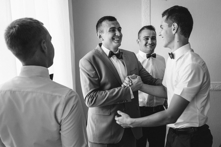 Handsome groom preparing for wedding ceremony in hotel roomの写真素材