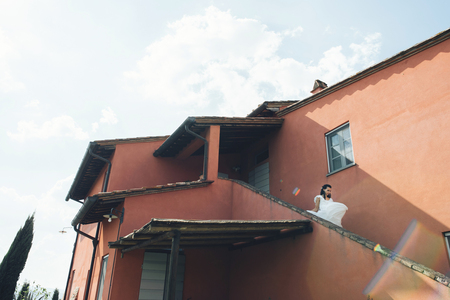 Stunning bride in white dress stands before wooden gates decoratの写真素材