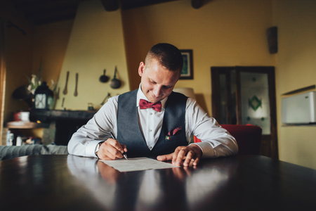 Handsome groom holds a box with wedding rings and stands beforeの写真素材
