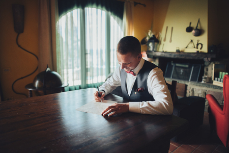 Handsome groom holds a box with wedding rings and stands beforeの写真素材