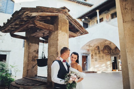 Lovely hugging wedding couple stands before the gates.の写真素材
