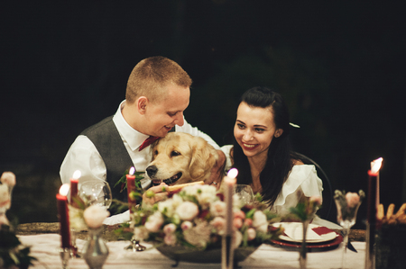 Bride and groom sitting at wedding table and smiling at cameraの写真素材