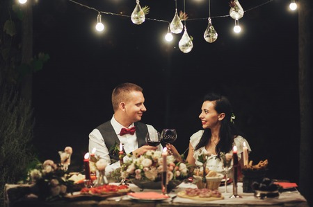 People clang glasses sitting at dinner table in sparkling lightsの写真素材