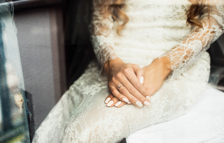 Elegant blonde bride putting on earrings closeup, preparing forの写真素材