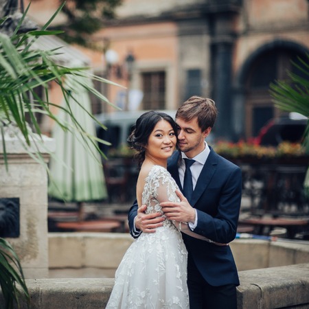 Elegant bride with groom walking near old catholic cathedralの写真素材