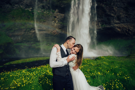Bride and groom walking in Iceland. Icelandic waterfall on the bの写真素材