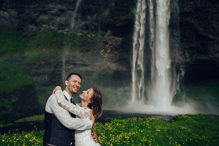 Bride and groom walking in Iceland. Icelandic waterfall on the bの写真素材