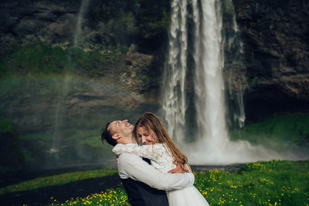 Bride and groom walking in Iceland. Icelandic waterfall on the bの写真素材
