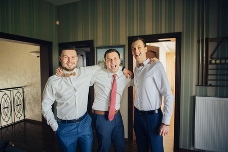 Stylish groomsmen and happy groom playing billiard  in the morniの写真素材