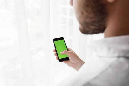 Close-up of male hands using smartphone near the window. Close upの写真素材