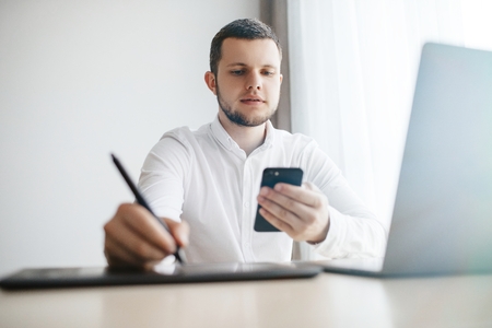 Young Man sitting at a table at home working on a laptop computerの写真素材