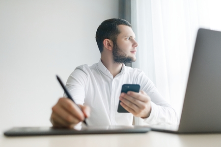 Photo of serious man uses modern digital smart phone deviceの写真素材