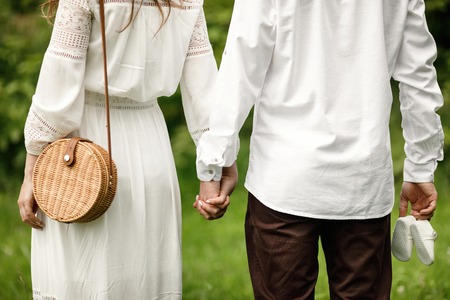 Happy and young pregnant couple hugging in nature. Pregnant couple holding their future baby boots.の写真素材