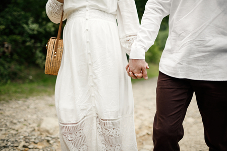 Happy and young pregnant couple hugging in nature. Pregnant couple holding their future baby boots.の写真素材