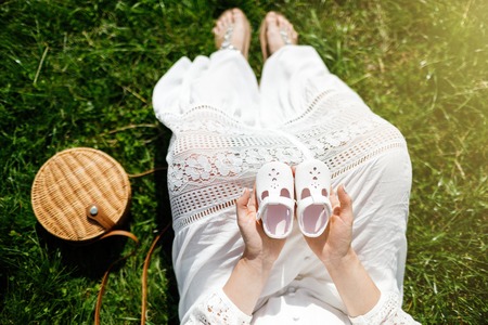 Young happy pregnant woman relaxing in nature. Close up of pregnant belly in nature.の写真素材