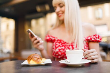 Young woman having italian breakfast with croissant and coffee aの写真素材