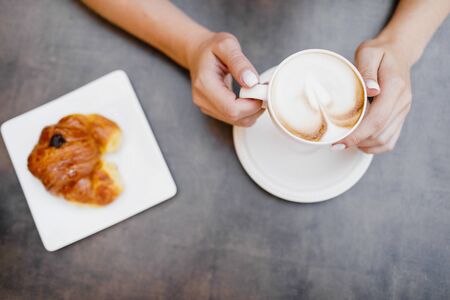 Young woman having italian breakfast with croissant and coffee aの写真素材