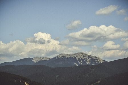 mountains surrounded by coniferous forest on the background of the charming cloudsの写真素材